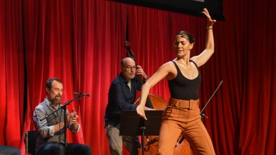 Woman dancing on stage with musicians playing behind her