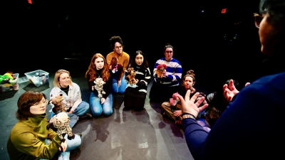 Professor teaching students to use puppets in drama therapy