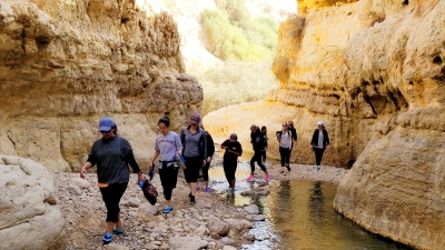 A group of students walks through a stream in a canyon