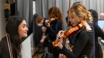 Two violinist collaborating while other students are in background