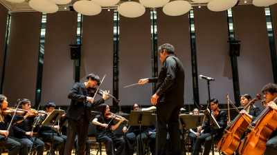 Symphony performing while conductor points to soloist violin player