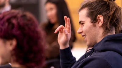Student raising his hand to speak in Ed Theatre class