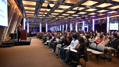 Professor at the podium in front of large audience of students and faculty