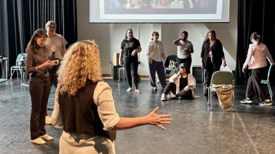 Professor working with theatre students in large room. Learning movements.