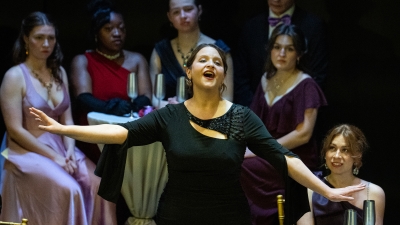 Opera singer in front of actors sitting at cafe style tables