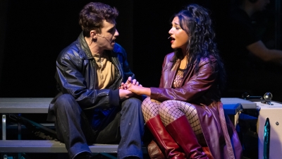 RENT characters Mimi and Roger sitting holding hands while singing to each other