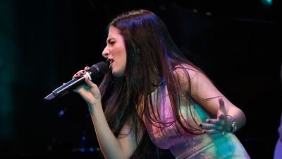 Student on stage dramatically singing into the microphone on stage