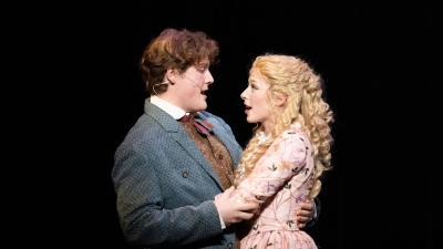 Two singers hugging and singing while looking into each others eyes lovingly.