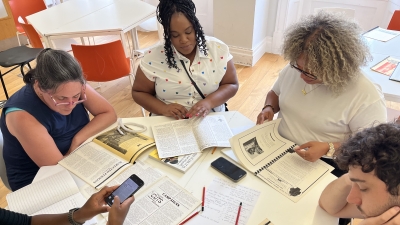 A group of students sit around a table, looking at magazines and newsletters