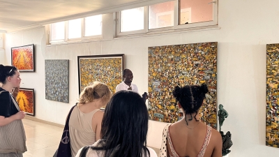 A group of students stands in an art gallery, listening to a docent