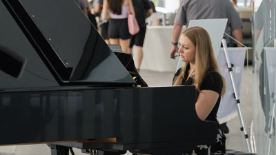 A woman plays piano on stage.