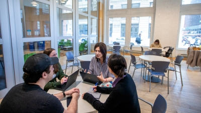 Four students sitting around a table in Pless lounge. 