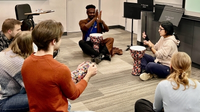 Students sitting on floor with instructor and instruments
