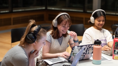 students sitting around a table with headphones and laptops open