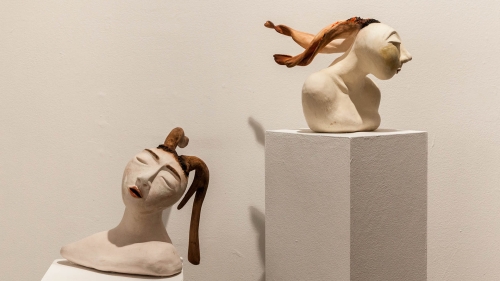 Two ceramic buffs facing in opposing directions, with braided hair floating from each head