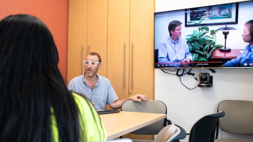 Man talking in front of Tv screen