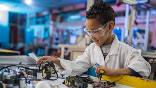 Boy with safety goggles studies electrical board.