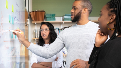 Students discussing calculations on a whiteboard