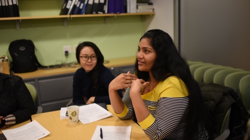 An MA student speaking while seated at a conference room table.