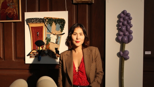 K. in front of art work. 