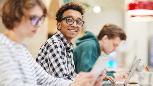 Smiling black student sitting between two white students