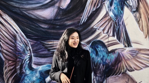 picture of MCC student in front of a mural outside
