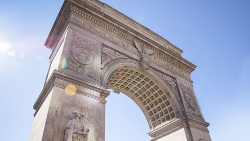 Towering view of WashingtonSquare arch against a bright blue sky