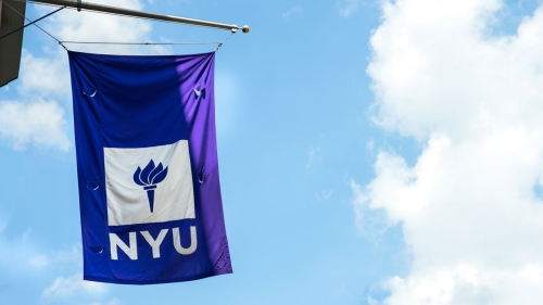 The NYU flag flying against a bright blue sky