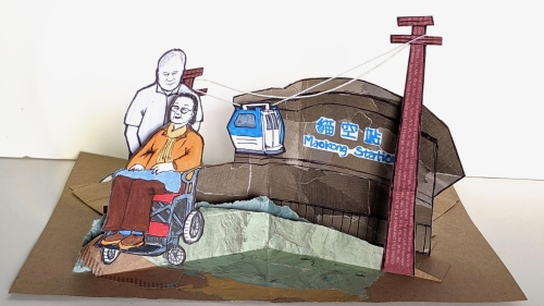 A pop-up card of woman in wheelchair pushed by man
