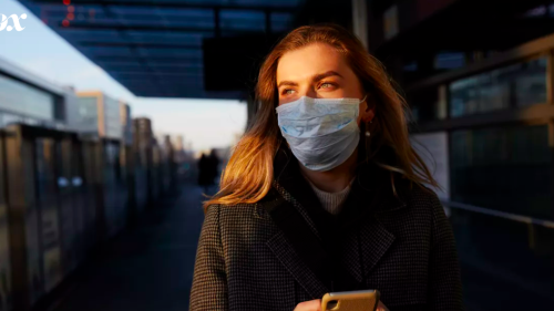 Women with mask on face on subway platform.