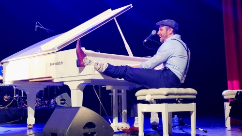 Arthur seated at a piano with one leg perched on the keys.