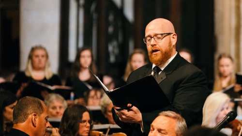 Errik Hood surrounded by orchestra sings solo.