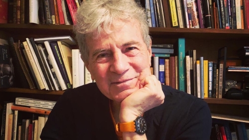 man smiling in front of bookshelf 