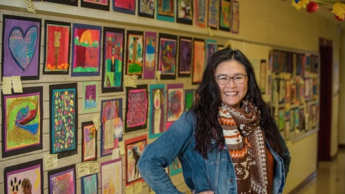Kim King standing in front of students' art work