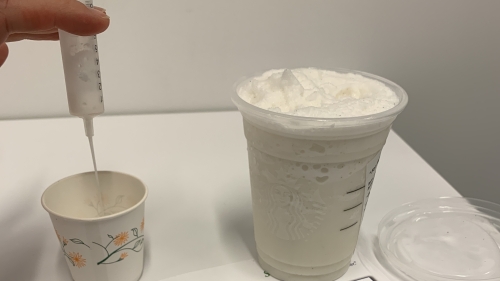 Syringe and two cups of liquid on top of a piece of paper with graphics outlining the International Dysphagia Diet Standardization Initiative guidance. 