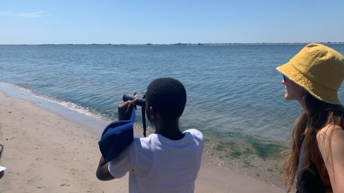 Student using binoculars at the beach