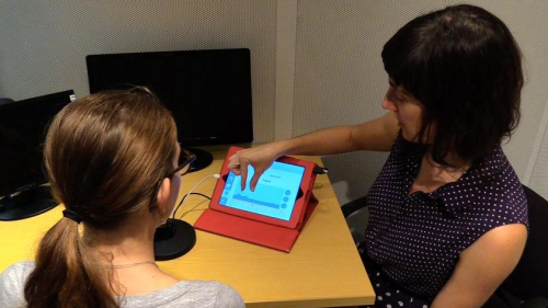 A photo of Heather Kabakoff directing a child to look at the screen of an iPad, where the staRt app is open. Below the photo are two animated stills from the app. One depicts ocean waves with the caption "Image of Poor /R/." The other shows ocean waves with the caption "Image of Good /R/."  