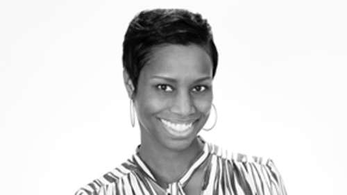 A black and white picture showing Holly smiling at the camera wearing a striped blouse.