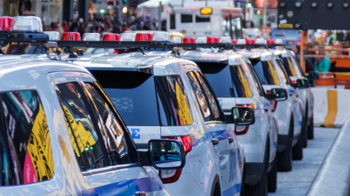 Four New York City Police cars parked on a busy New York City street.