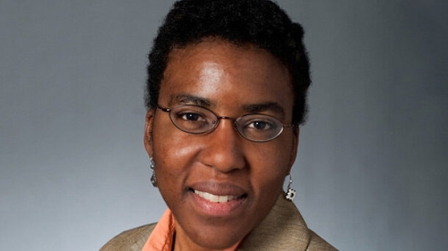 A headshot of Anne Washington, a Black woman with glasses smiling at the camera. 