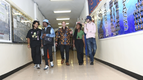 Billy Green walks down a school hallway with four students.