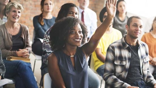 A woman raising her hand to ask a question.
