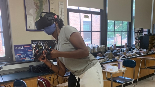 A student, wearing a VR headset, plays BOXVR in a classroom. 