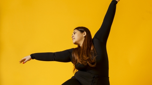 Woman posing in dance move in front of yellow screen