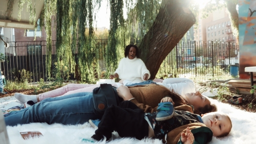 Family sitting outside on a blanket.