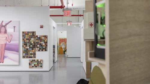 A picture of the hallways of the BFA art studios. Some paintings appear on the wall to the left of the image.