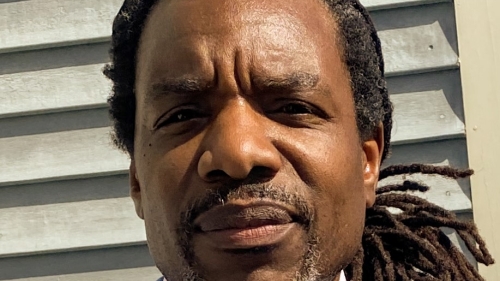 Educator, Jamel Adkins Sharif shares a modest smiile in a photo