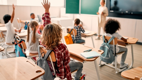 Classroom with students raising their hands.