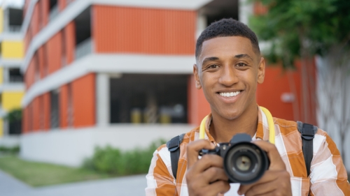 Student Photographer smiles with camera in hand