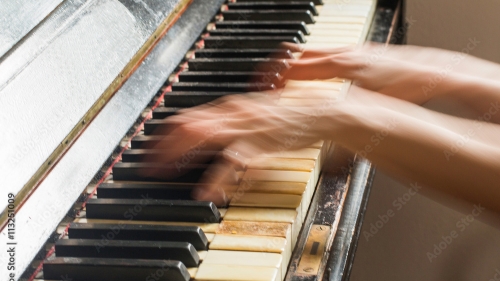 hands playing piano very fast, so fast they are blurry